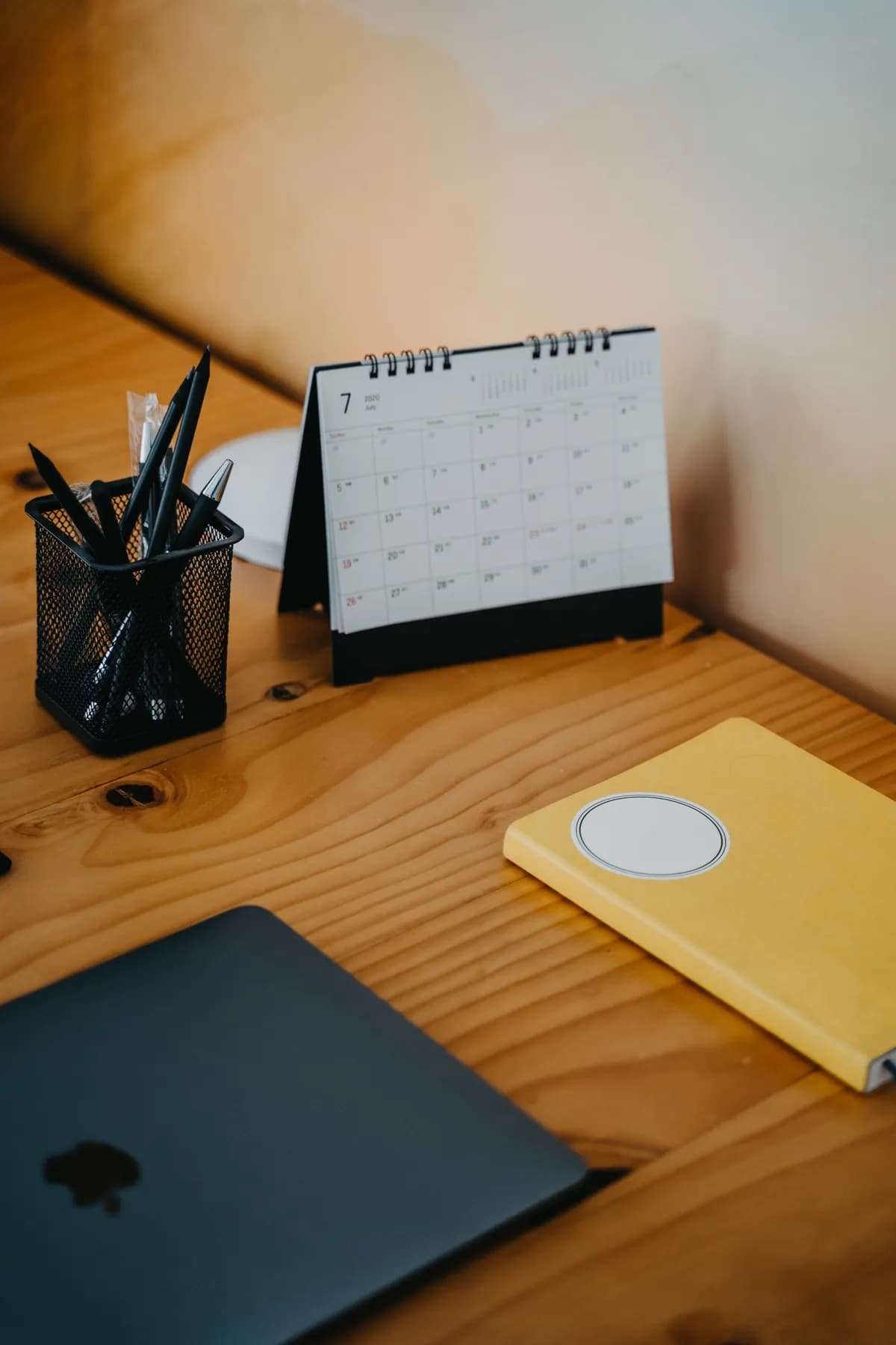 A desk calendar, notebook and laptop on a wooden desk