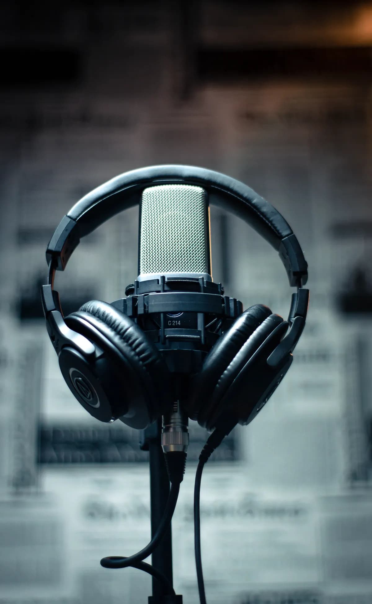 A studio microphone with a pair of headphones resting on it